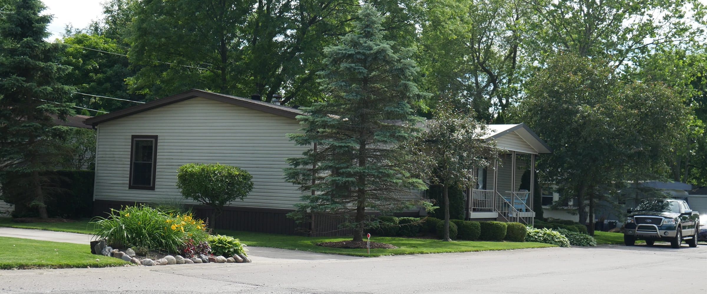 Tree-lined street with manufactured homes at Lapeer Meadows