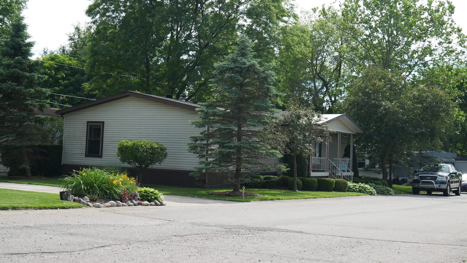 Tree-lined street with manufactured homes at Lapeer Meadows